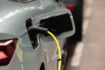 A car is being charged with a yellow cable plugged into the back of it.
